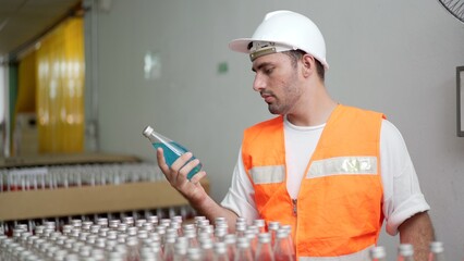 quality control officer inspecting the manufacturing line and computer system in the beverage bottling factory.