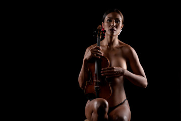 Fototapeta na wymiar Beautiful sexy woman emotion in nude.hold violin on black background, in emotion feeling committed.