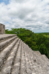 Looking out across ancient Mayan stone steps towards the jungle canopy and sky in Calakmul, Mexico