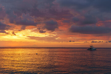 Pastel sunset in Cozumel with a boat on the horizon and calm water