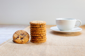 Light brown cookies and white mug are placed on the tablecloth in the kitchen.