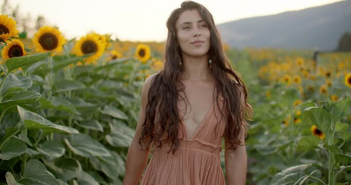 Female model in sunflower field wearing dress at sunset, happy