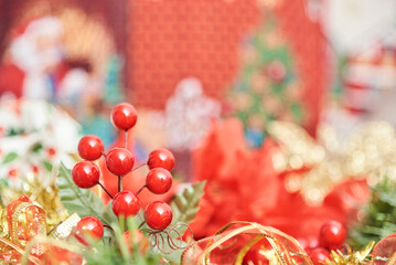 Traditional Christmas theme background with red, green and gold. Red berries, ribbons and leaves in foreground. Composition with selective focus and copy space.