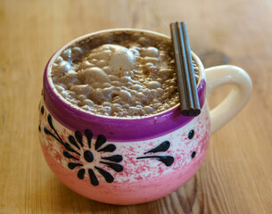 Bubbling hot chocolate served in a decorative pink and purple mug with chocolate on top. - obrazy, fototapety, plakaty