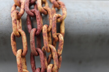 Yellow and brown rust chains wrapped around metal car guard rail