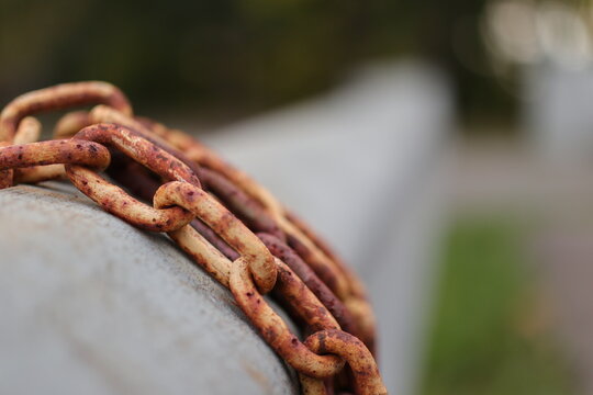 Yellow and brown rust chains wrapped around metal car guard rail