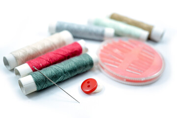 Rows of sewing threads of various colors, sewing needles and shirt buttons