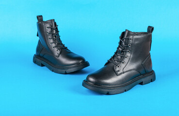 A pair of high leather boots on a bright blue background.