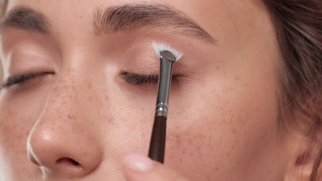 Caucasian Woman makes makeup. Young woman paints her eyelashes with an eyelash brush. Cosmetic concept. Beautiful brunette model doing make-up. 4k Slow motion footage. Closeup view.