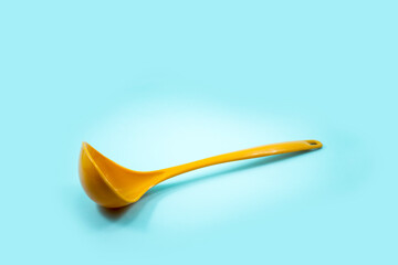 yellow ladle used to scoop soup isolated on a turquoise