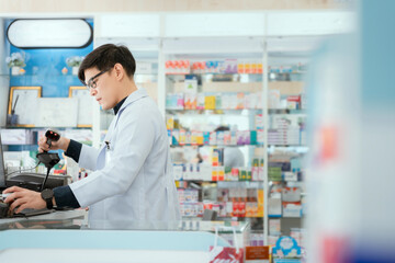 Naklejka na ściany i meble A male pharmacist checks drug stocks in a community pharmacy.