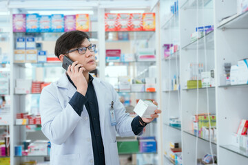 A male pharmacist checks drug stocks in a community pharmacy. use the phone to talk © 2B
