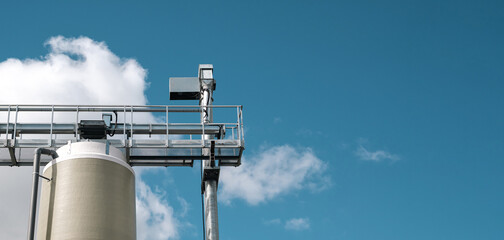 A vertical row of silos with fodder for cattle on a farm, against the background of the sky © mira_y