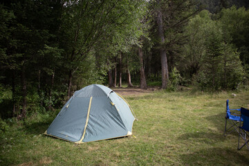 Camping in a tourist forest. A green tent set up on a picnic spot.