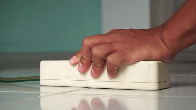 Hand plug and unplug the phone charger from the electric socket on the floor. Close up hand unplug the charger from charging station