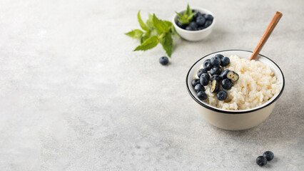 Rice milk porridge with blueberries in a bowl close-up. The concept of a healthy and tasty breakfast. Copy space