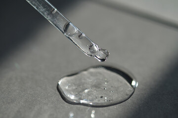Pipette with spilled cosmetic oil or serum on a gray background.