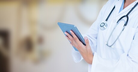 Mid section of female doctor using digital tablet in hospital 