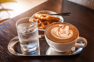 Hot coffee latte with latte art milk foam in a swan shape in cup mug and Homemade Belgian Waffles with honey on wood desk on top view. As breakfast In a coffee shop at the cafe,during business work.