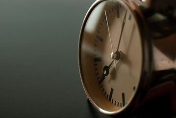 Closeup vintage clock selective focus at number 7 o'clock on a dark background.