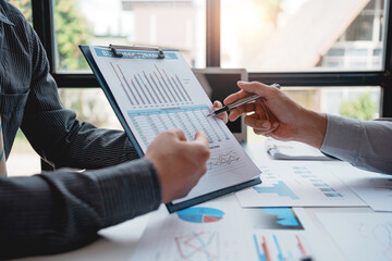 Two businessman working together to plan investment at the meeting. Close-up of businessman advisor pointing to graph and chart, analyzes financial report and profit deficit.