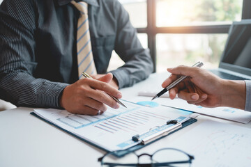 Two businessman working together to plan investment at the meeting. Close-up of businessman advisor pointing to graph and chart, analyzes financial report and profit deficit.