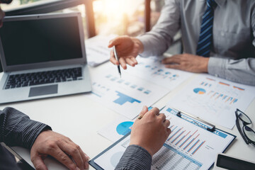 Two businessman working together to plan investment at the meeting. Close-up of businessman advisor pointing to graph and chart, analyzes financial report and profit deficit.