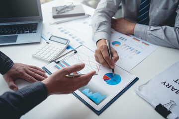 Two businessman working together to plan investment at the meeting. Close-up of businessman advisor pointing to graph and chart, analyzes financial report and profit deficit.