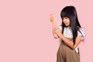 Asian little kid 10 years old scratching itch arm from a mosquito bite at studio shot isolated on...