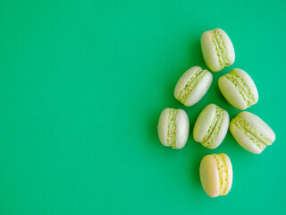 French mint pistachio green tea macarons shaped as Christmas tree on green background. Top view flat lay, copy spase