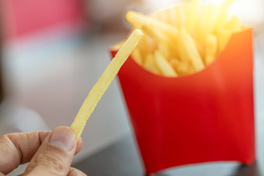 french fries. closeup male hand holding golden potato stick fry popular american fast food.