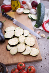 eggplant on wooden cutting board and vegetables at domestic kitchen
