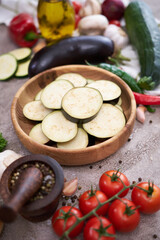 sliced eggplant in a wooden bowl and vegetables at domestic kitchen