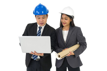 Asian businessman in black suit wearing a blue hardhat, typing on laptop computer keyboard. Young assistant holding construction drawings of real estate project, stand next to him.