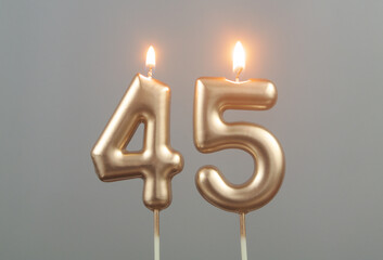 Burning gold birthday candles on gray background, number 45 - obrazy, fototapety, plakaty