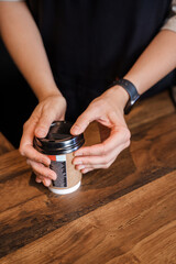 Fototapeta na wymiar Female barista working in coffee bar preparing coffee in plastic cup.