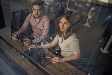 Fototapeta na wymiar Shot from outdoors of two people in coffee bar looking through window.