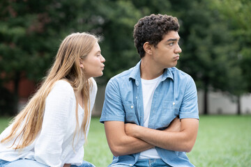 Teenager girl trying to kiss distracted boyfriend. Hispanic boy ignoring girlfriend