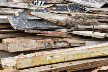 Construction waste after dismantling the formwork of a reinforced concrete foundation. Utilization of construction waste. Old boards, beams and formwork panels at a construction site.