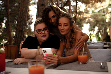 Group of female friends, plus size with thin girls sit in cafe and drink the drinks.