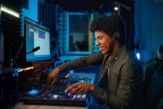 Young man paying music on sound mixer in radio station