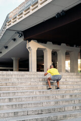 Unrecognizable adult man doing squats exercises on stairs outdoor