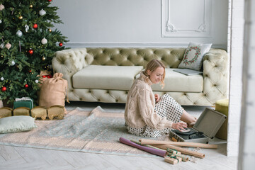 Woman wrapping gifts and enjoying Christmas atmosphere at home.