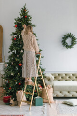 Woman decorating home for Christmas holidays. Stylish interior. 