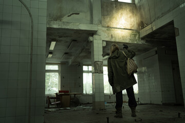 Obraz na płótnie Canvas Nuclear disaster survivor in a post apocalyptic setting, woman stalker or soldier in abandoned building, environmental disaster and chemical warfare concept