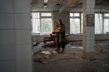 Nuclear post apocalypse life after doomsday concept. Grimy female survivor reading in abandoned...