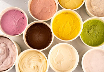 Ice creams in bright colors served in plastic tubs.