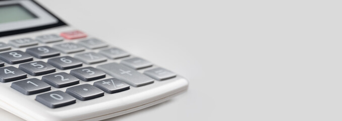 close up white calculator on gray background for business financial concept. crop image of calculator. copy space
