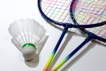 Colorful badminton rackets and plastic shuttlecock on isolated white background with selective focus. Game, sport, fun concept.