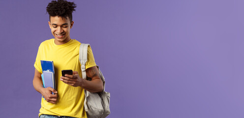 Back to school, university concept. Portrait of pleased good-looking male student texting friend,...